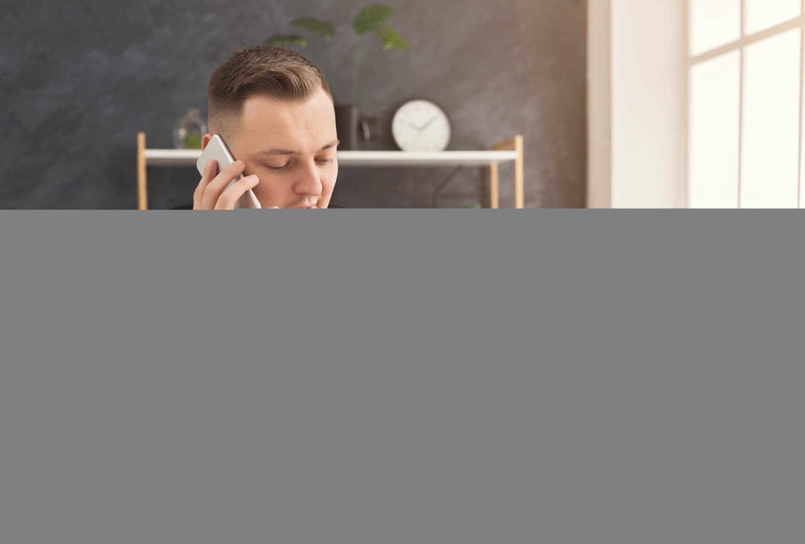 Masasında belgelerle çalışan bir adam telefonda konuşurken not alıyor